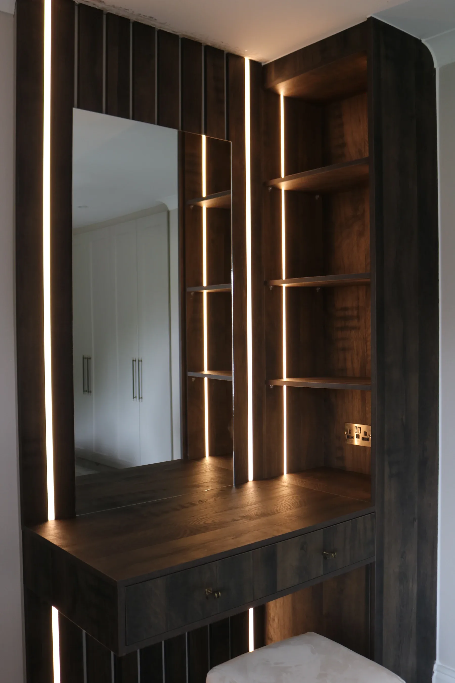 Dark wood dressing area with LED-lit mirror and shelves, real installation
