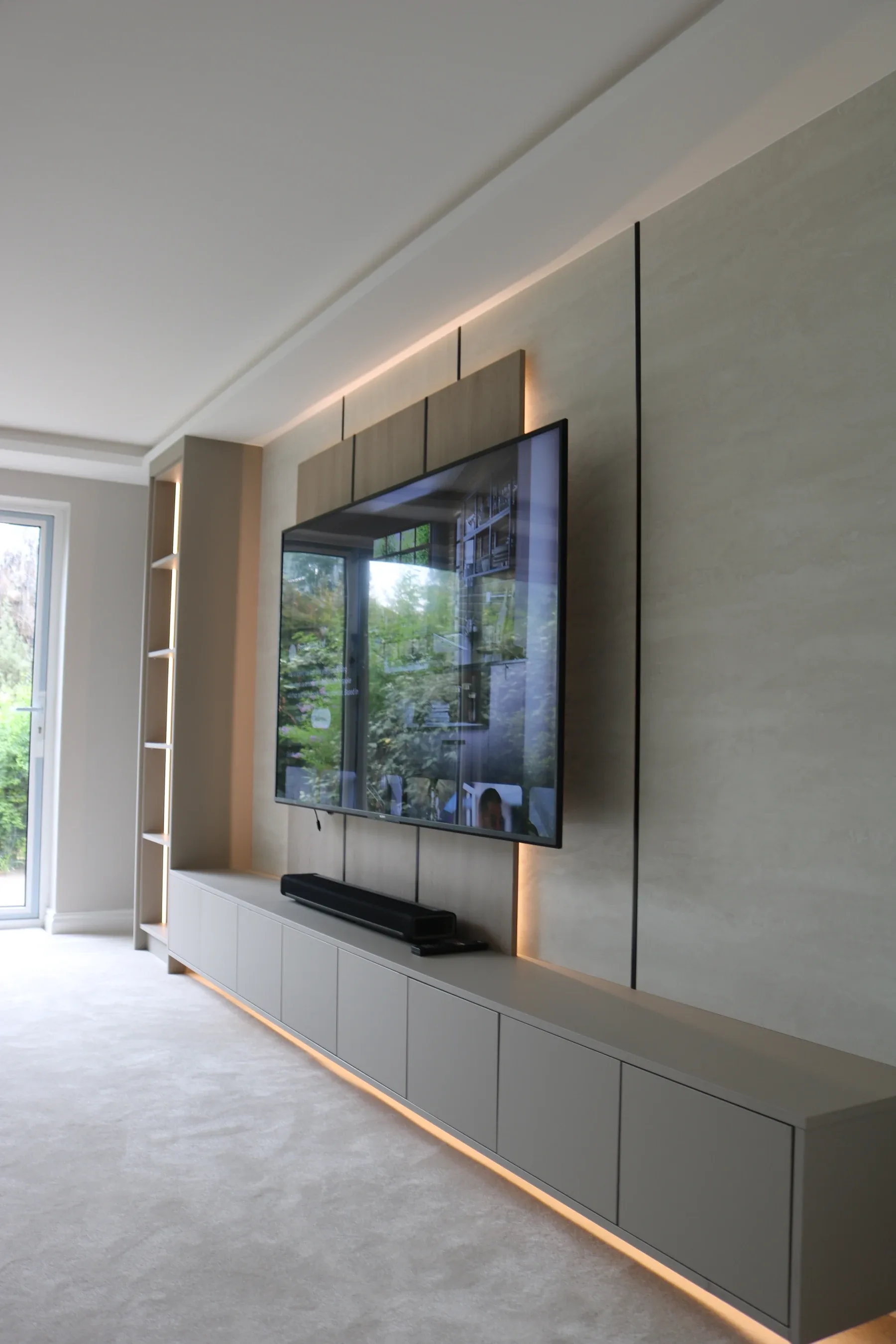 Media wall shelving with LED lighting at dusk, real installation