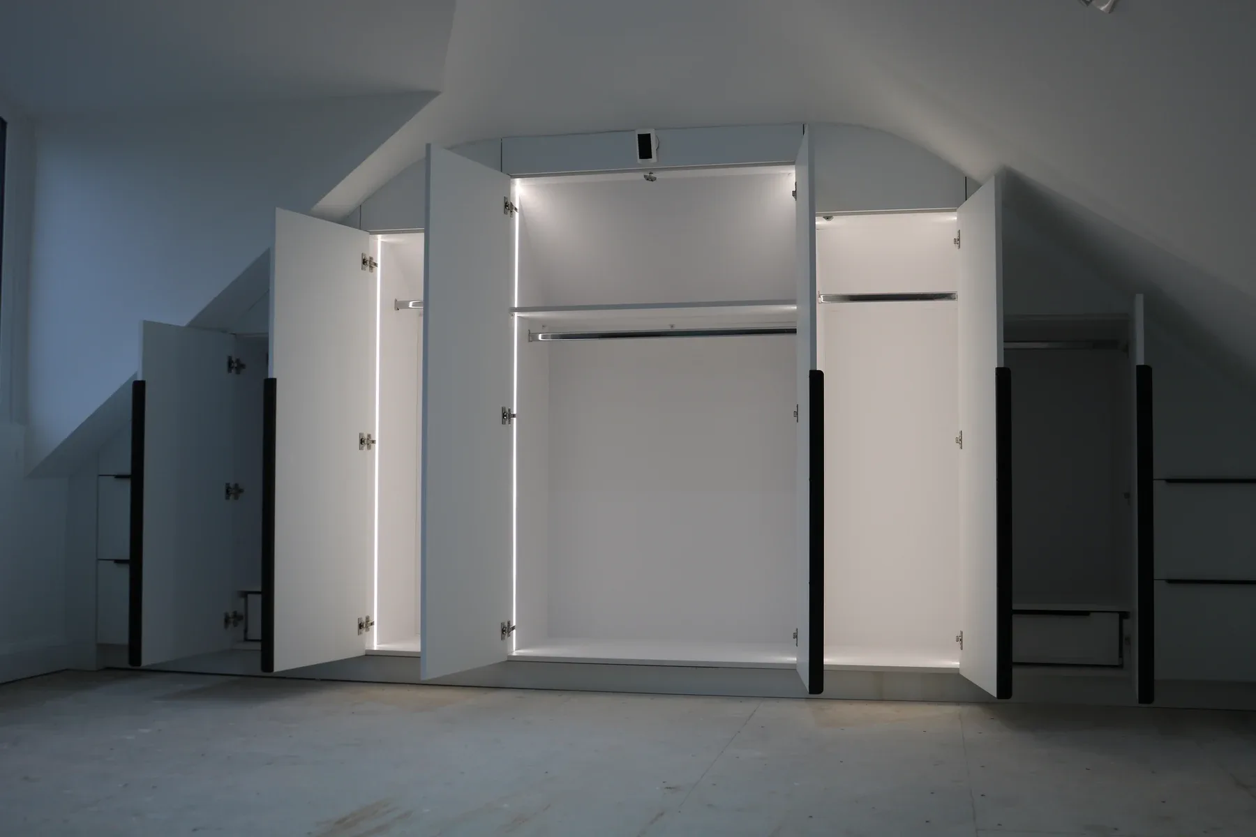 Fitted wardrobes cut to a sloped loft ceiling with LED-lit interiors, real installation