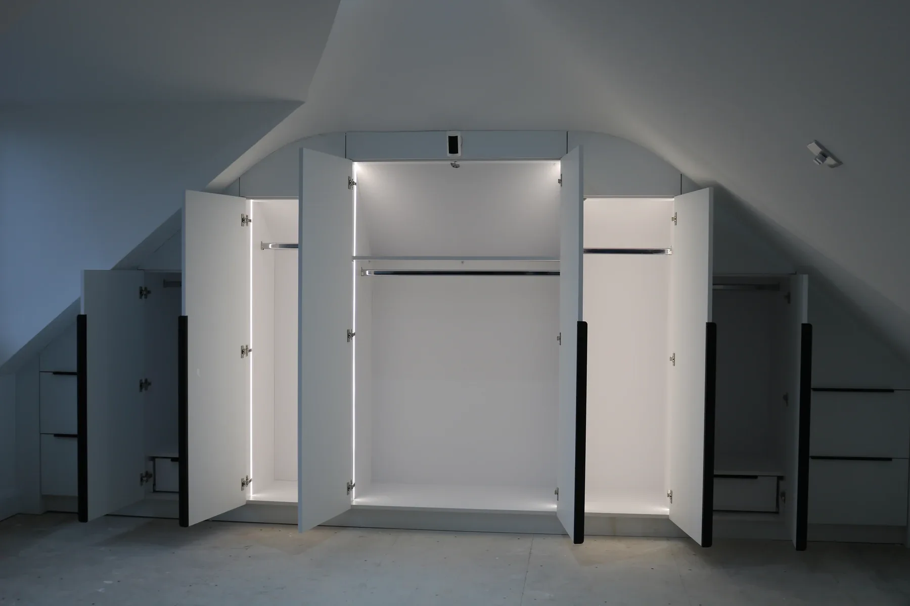 Fitted wardrobes scribed to a sloped loft ceiling with LED-lit interiors, real installation